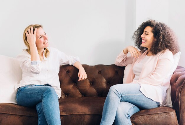 Mujeres alegres que hablan en el sofá