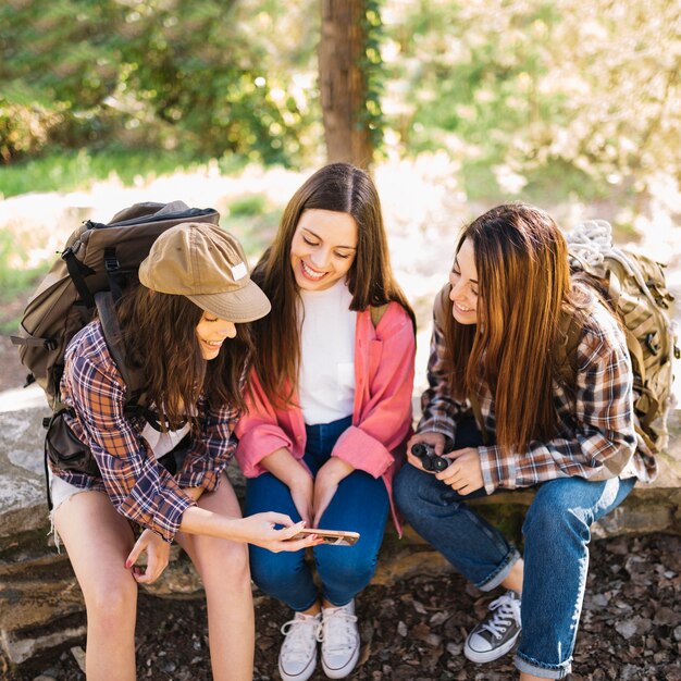 Mujeres alegres que usan smartphone en viaje