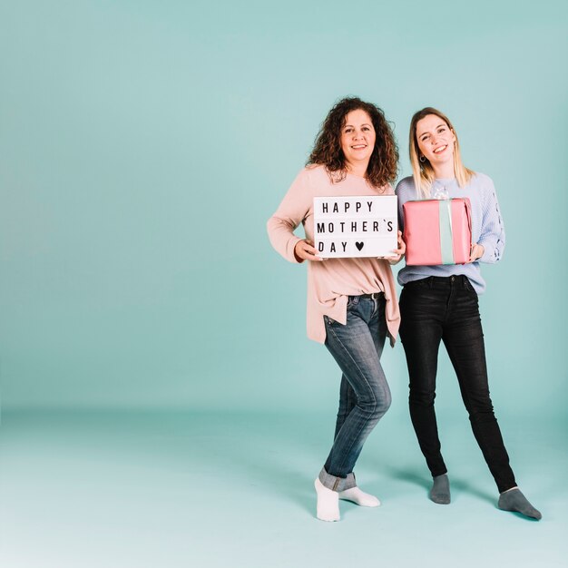 Mujeres alegres con regalos y escribiendo el día de la madre