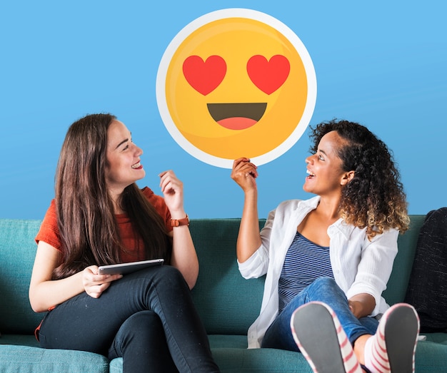 Foto gratuita mujeres alegres sosteniendo un icono de emoticon de ojos de corazón