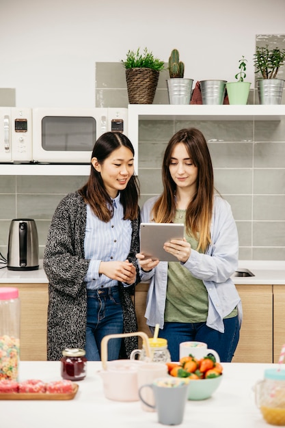 Foto gratuita mujeres alegres con tableta en la cocina