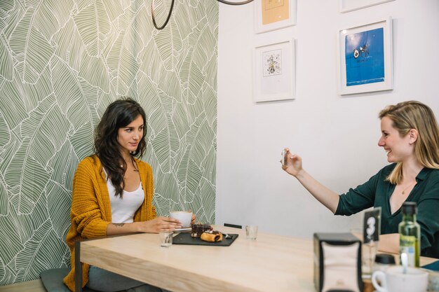 Mujeres alegres tomando fotos en café