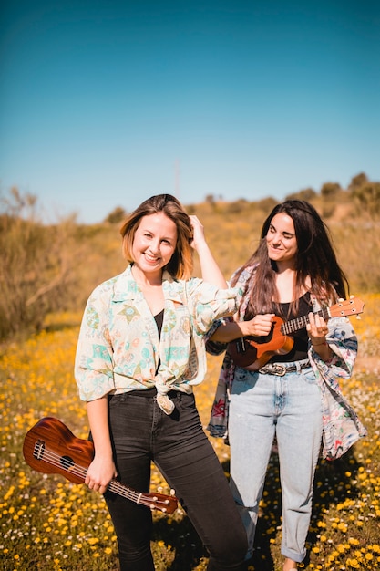 Mujeres alegres con ukeleles en el campo