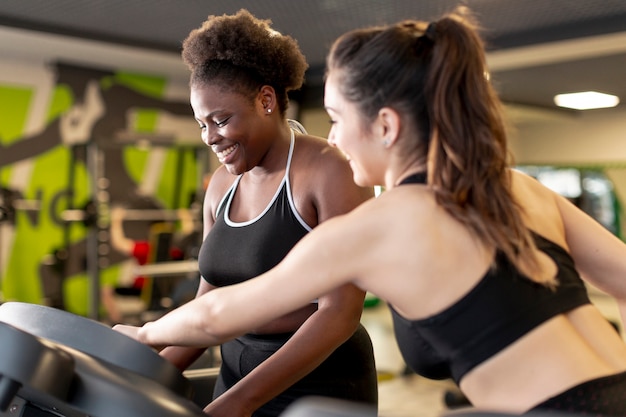 Mujeres de alto ángulo en el gimnasio entrenando juntas