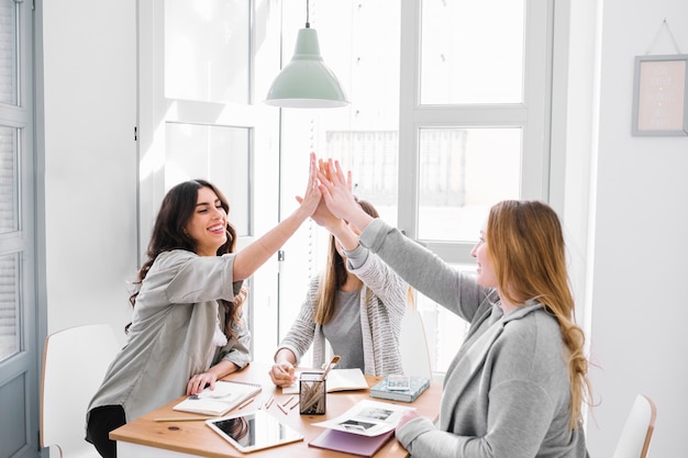 Foto gratuita mujeres de alto fiving en la mesa