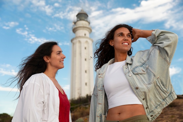 Foto gratuita mujeres con ángulo bajo posando con un faro