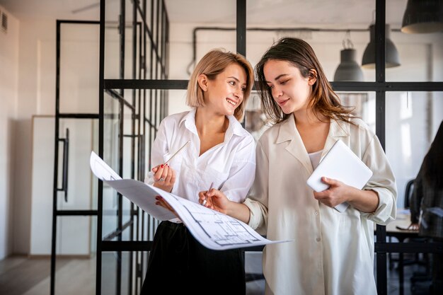 Mujeres de ángulo bajo que verifican resultados de negocios