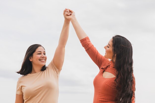 Mujeres de ángulo bajo tomados de la mano