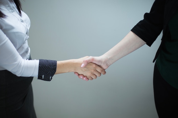 Mujeres anónimas dándose la mano en gris