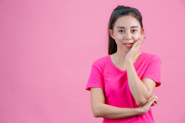 Las mujeres asiáticas blancas usan camisas rosas. Ponga su mano izquierda en su cara Sobre la rosa.