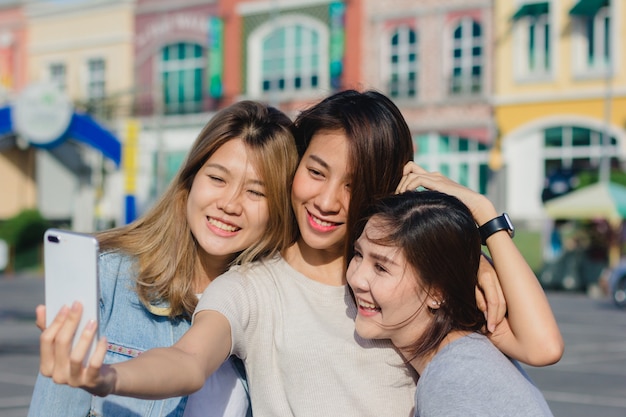 Mujeres asiáticas hermosas atractivas de los amigos que usan un smartphone. Adolescente asiático joven feliz en la ciudad urbana