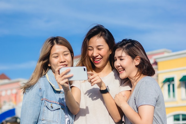 Mujeres asiáticas hermosas atractivas de los amigos que usan un smartphone