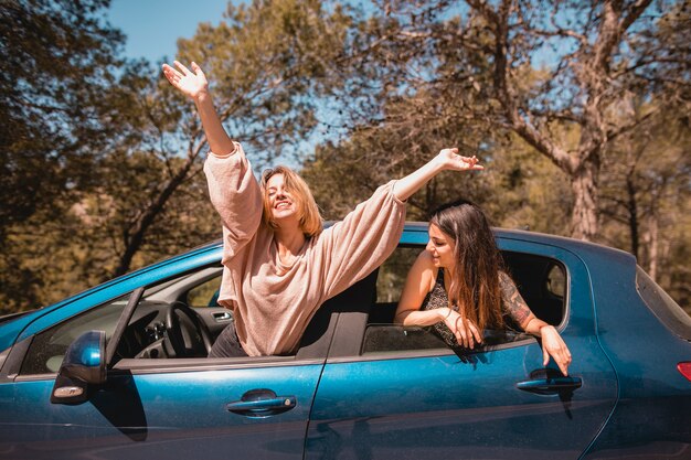 Mujeres asomándose a las ventanas de los automóviles