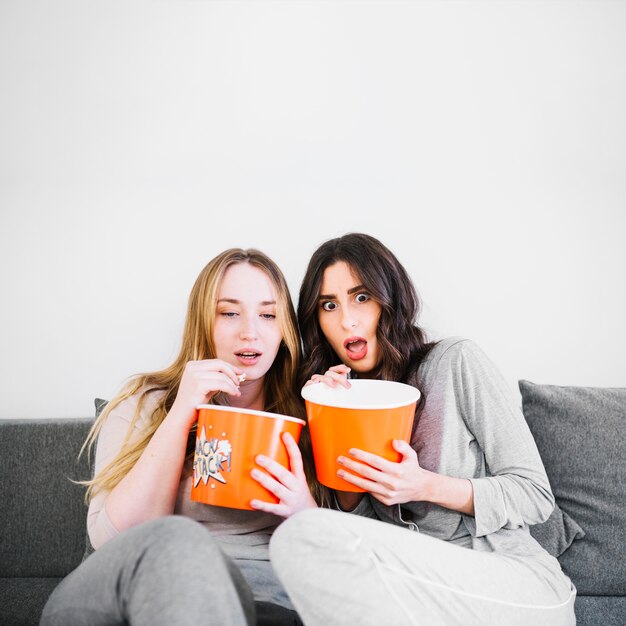 Mujeres asustadas comiendo palomitas de maíz