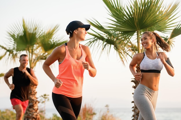 Mujeres atléticas sonrientes corriendo en la naturaleza y hablando entre ellas.