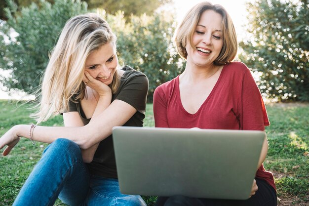 Mujeres atractivas que usan la computadora portátil en la tierra