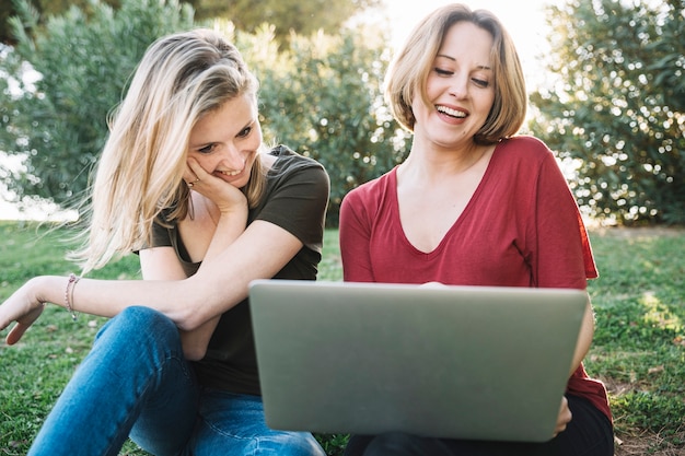 Mujeres atractivas que usan la computadora portátil en la tierra