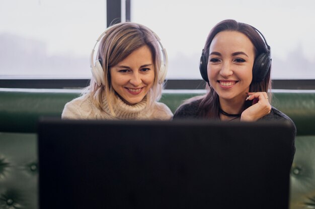 Mujeres con auriculares mirando portátil