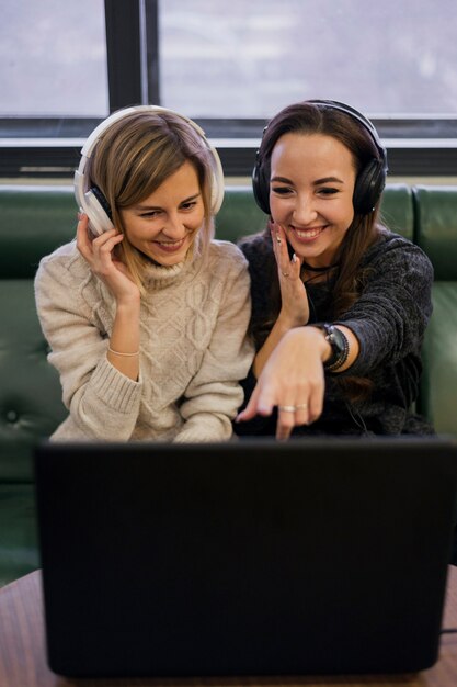 Mujeres con auriculares mirando portátil