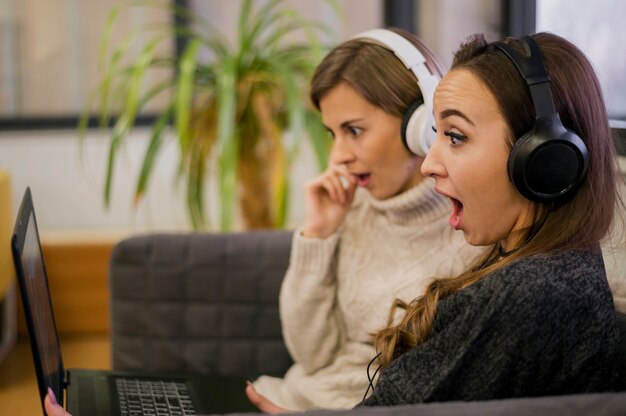 Mujeres con auriculares mirando portátil