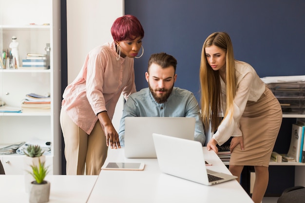 Mujeres ayudando colega con proyecto