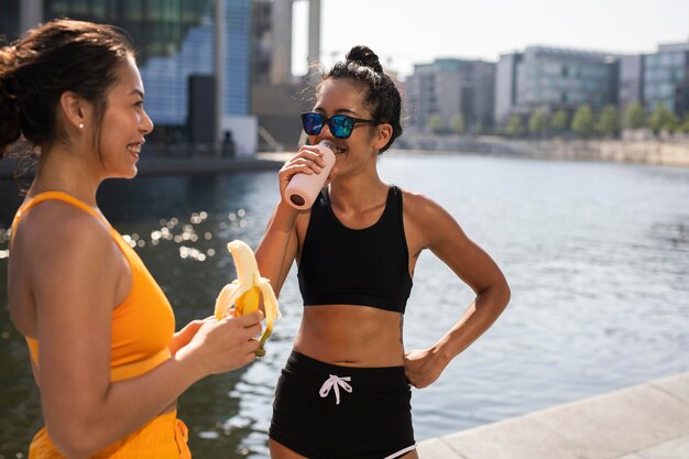 Foto gratuita mujeres con banana y agua de tiro medio.