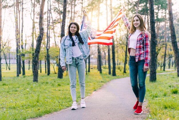 Mujeres con bandera de USA caminando al aire libre.