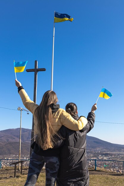 Mujeres con banderas de ucrania contra el fondo del cielo y las montañas