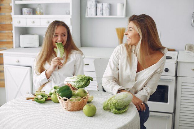 Mujeres bellas y deportivas en una cocina con verduras