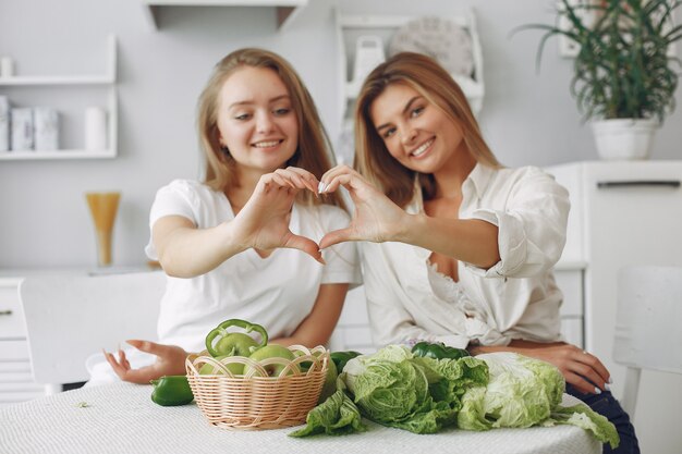 Mujeres bellas y deportivas en una cocina con verduras