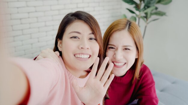 Mujeres blogger asiáticas que usan un teléfono inteligente autofoto y graban vlog video en la sala de estar en casa