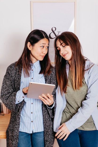 Foto gratuita mujeres bonitas de pie con tableta digital