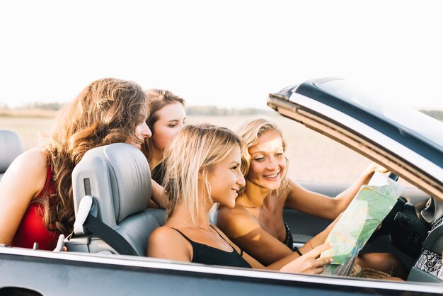 Mujeres bonitas que miran el mapa en coche