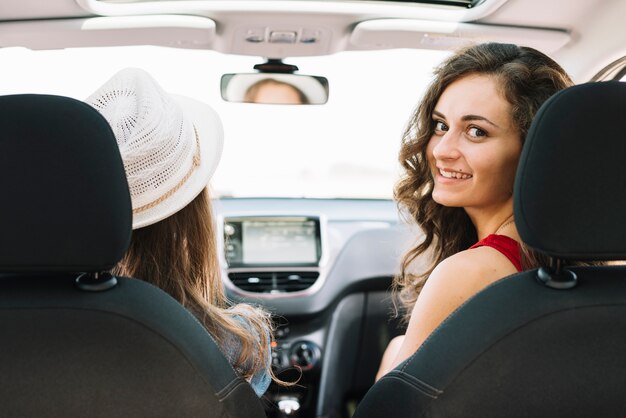 Mujeres bonitas que se sientan en el coche y la conducción