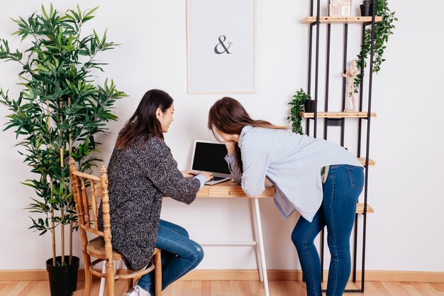 Mujeres bonitas que trabajan en la computadora portátil