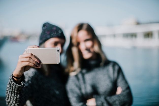 Mujeres borrosas haciendo un selfie con agua en el fondo