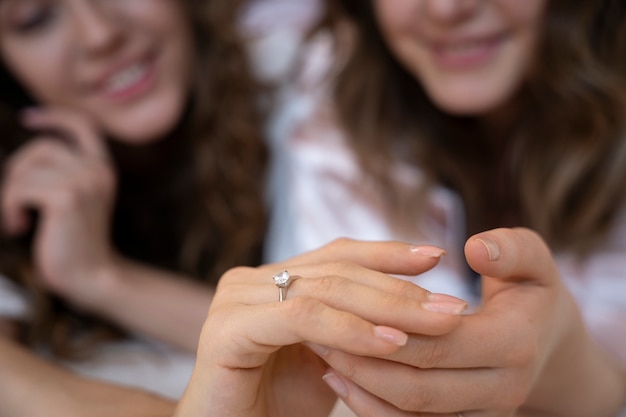 Mujeres borrosas sonrientes con anillo de compromiso