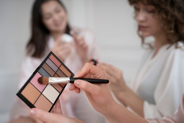 Mujeres borrosas sonrientes con paleta de maquillaje