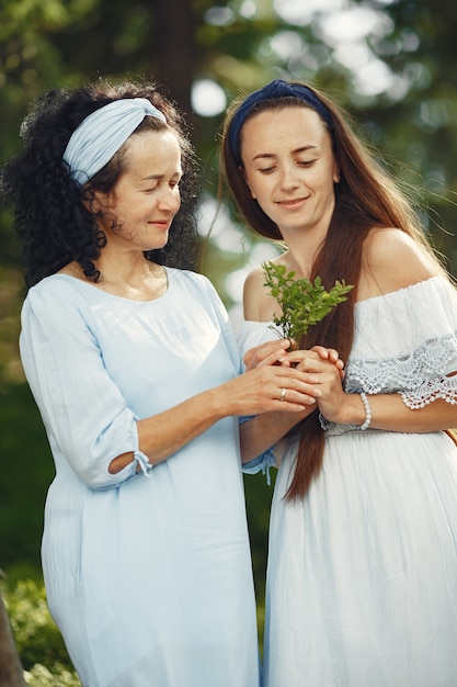 Mujeres en un bosque de verano. Dama con un vestido azul. Familia posando y abrazándose.