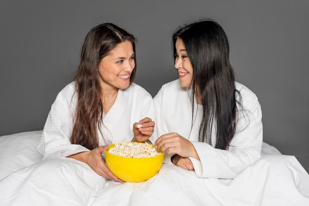 Mujeres en la cama comiendo palomitas de maíz