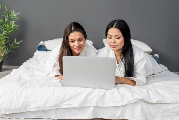 Mujeres en cama usando laptop