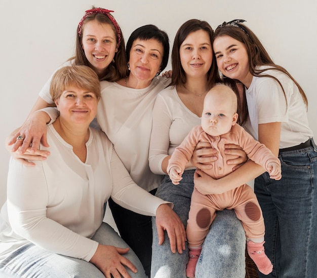 Mujeres en camisas blancas posando juntas y bebé