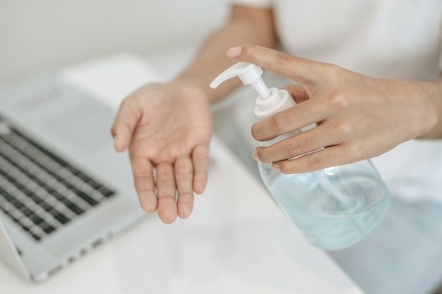 Mujeres con camisas blancas que presionan el gel para lavarse las manos y limpiarse las manos.