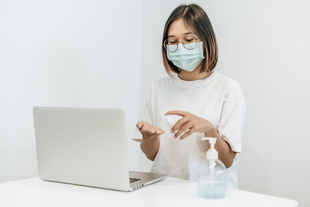 Mujeres con camisas blancas que presionan el gel para lavarse las manos y limpiarse las manos.