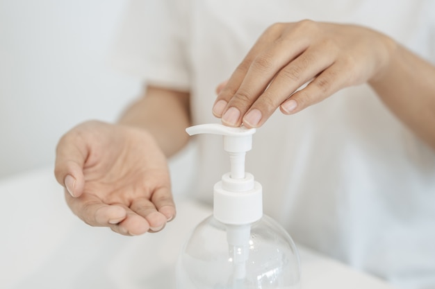 Mujeres con camisas blancas que presionan el gel para lavarse las manos y limpiarse las manos.