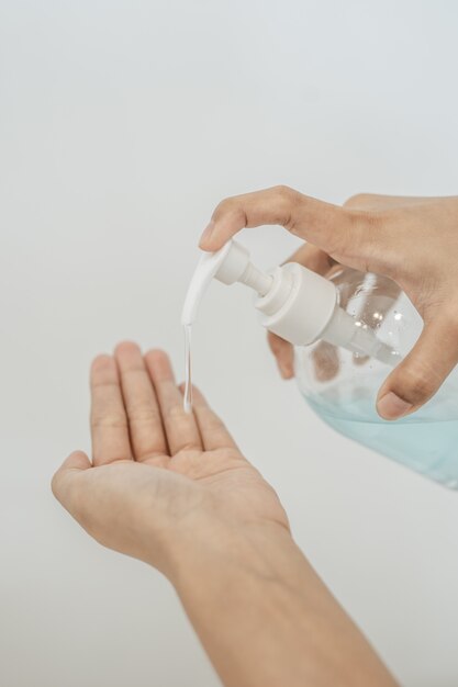 Mujeres con camisas blancas que presionan el gel para lavarse las manos y limpiarse las manos.