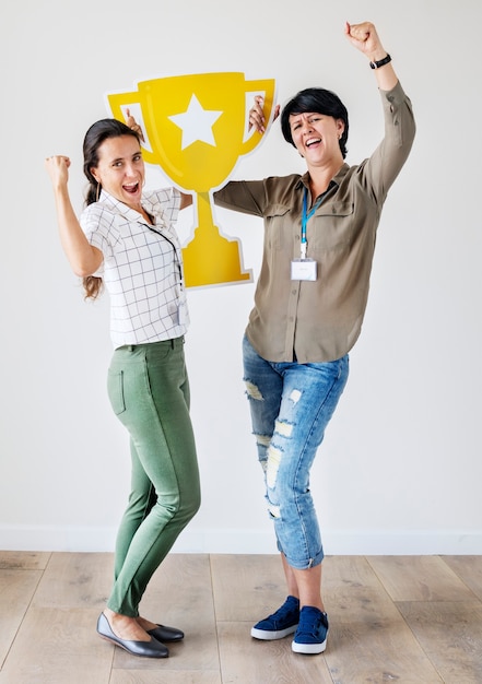 Mujeres celebrando su éxito con un trofeo.