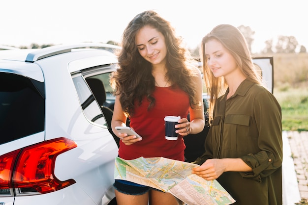 Mujeres cerca del coche con hoja de ruta