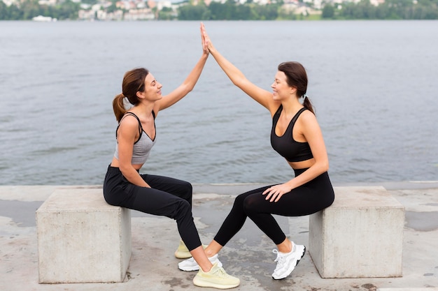 Mujeres chocando los cinco mientras hacen ejercicio al aire libre