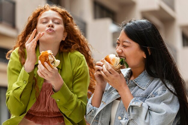 Mujeres comiendo deliciosas hamburguesas afuera